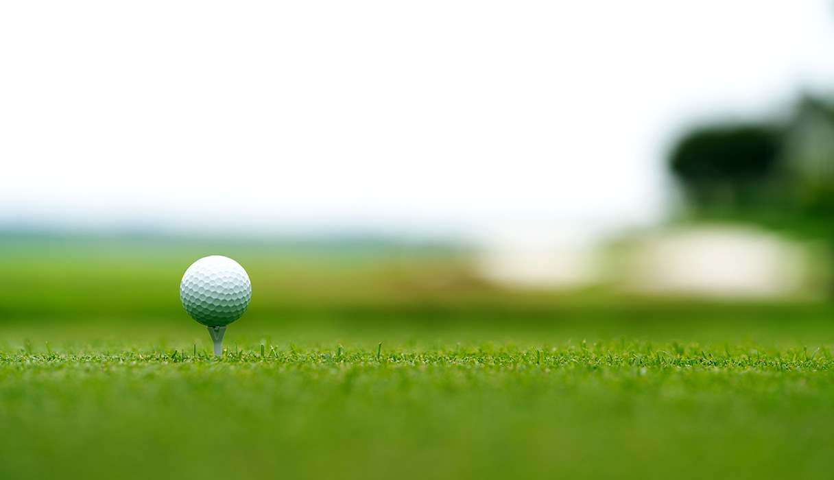 Portrait shot of a golf ball on a tee at Two Rivers course with a blurred background.