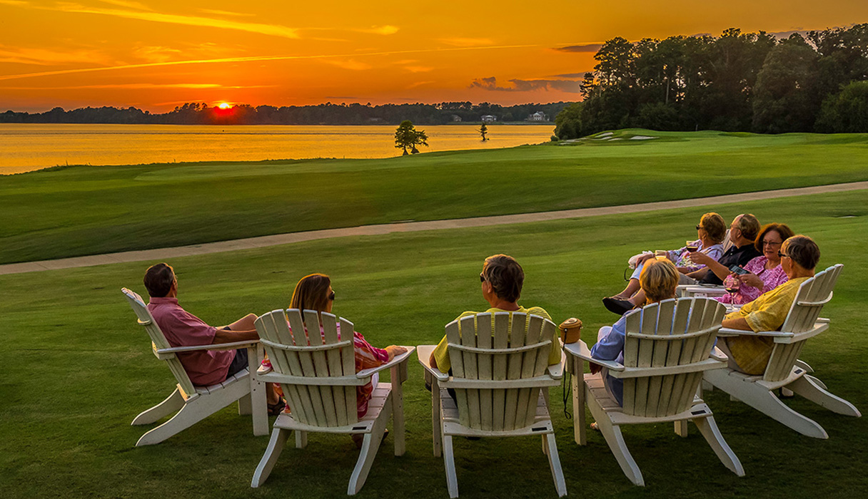 Members of the Two Rivers Country Club sitting in Adirondack lounge chairs overlooking the beautiful James River at Sunset.