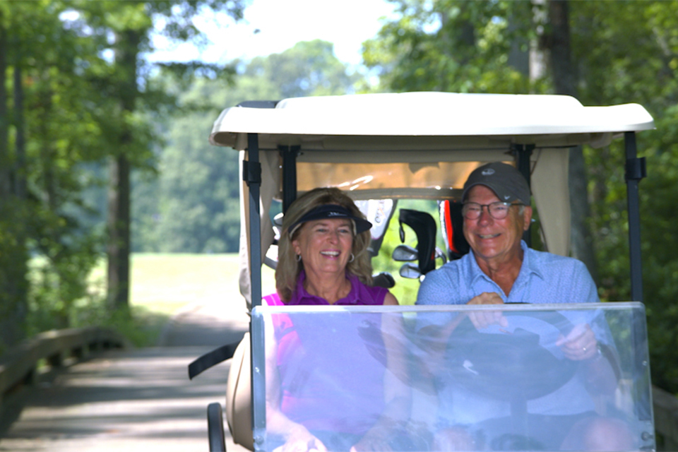 two members riding in a Two Rivers golf cart